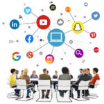 business people seated around round table in white room with social media icons floating above