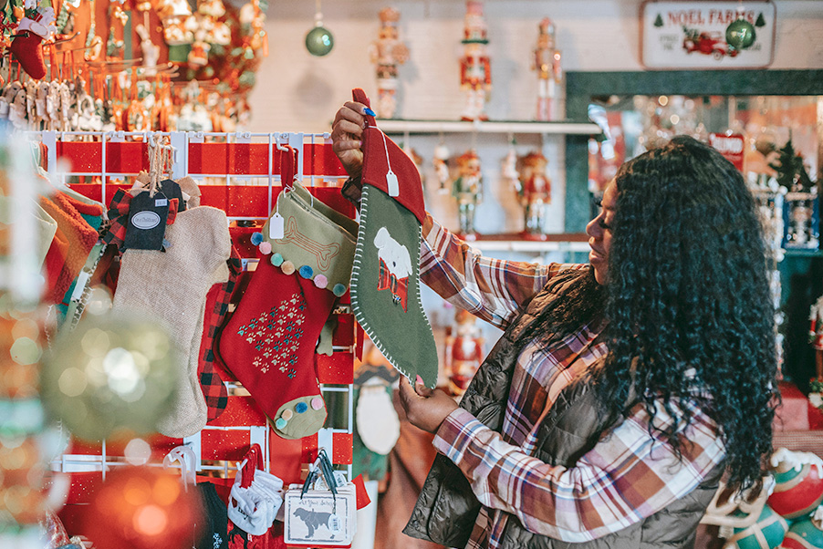 woman in store looking at Christmas stockings and holiday decorations