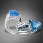 close up photo of white gold and blue diamond ring with dramatic lighting on gray background