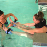 two women performing water therapy rehabilitation in pool