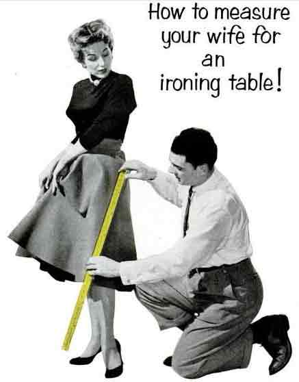 image from a vintage sexist print ad with a 1950s husband kneeling next to his wife and measuring her leg with a yardstick, with the headline "How to measure your wife for an ironing table!"